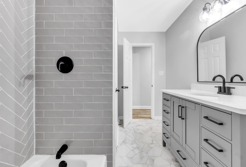 Full bathroom with marble finish floors, vanity, and washtub / shower combination