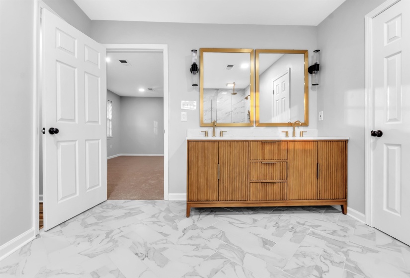 Bathroom featuring baseboards, marble finish floors, double vanity, and a marble finish shower