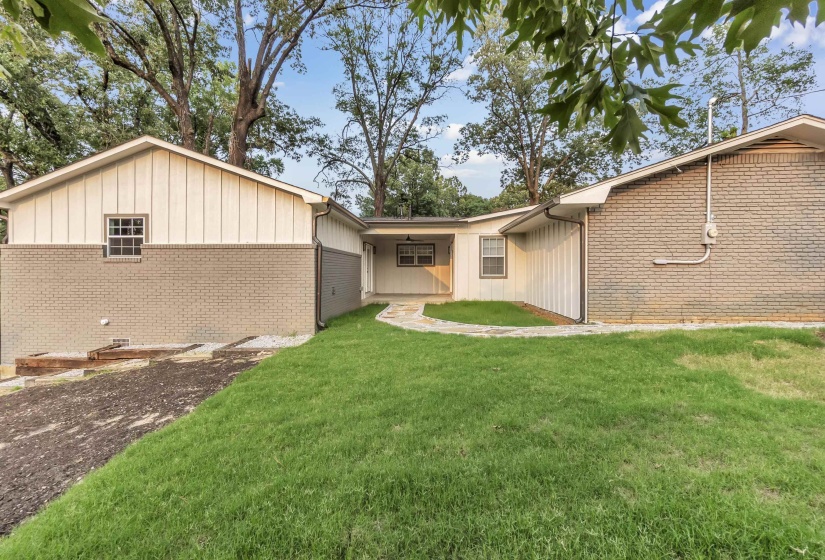 Rear view of property with brick siding, a yard, and board and batten siding
