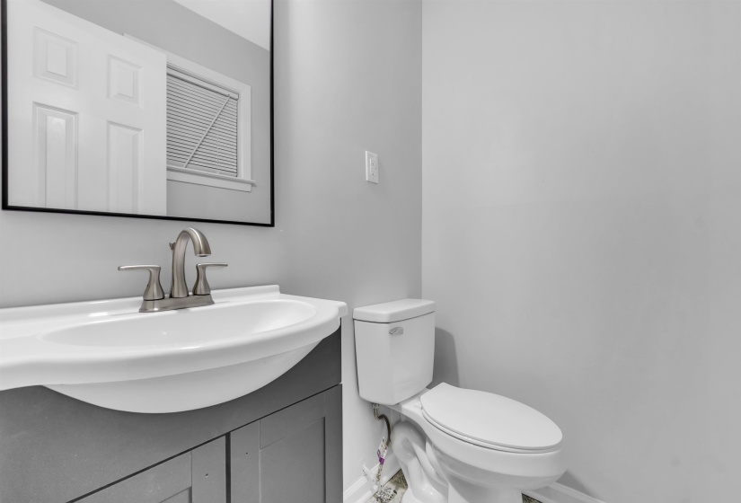 Half bath featuring baseboards, vanity, and toilet