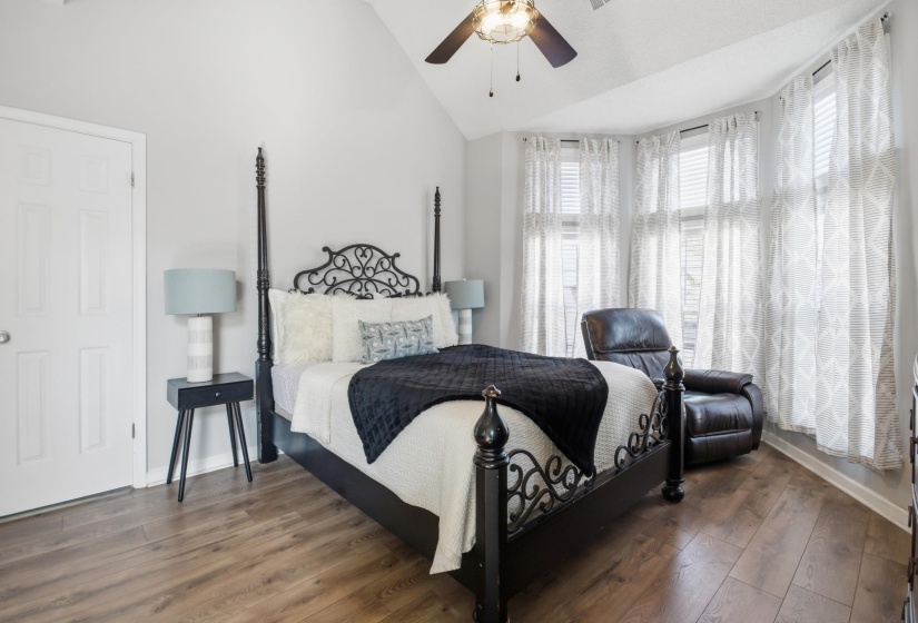 Bedroom with dark wood-style flooring, lofted ceiling, and ceiling fan