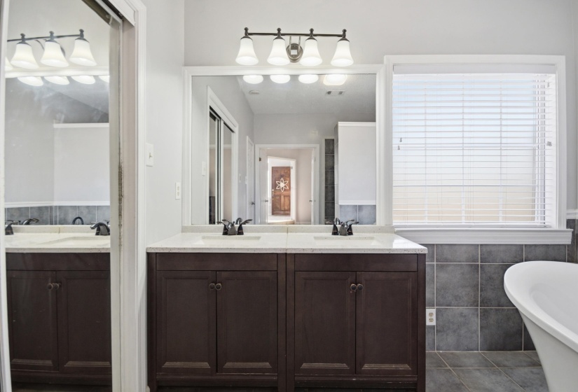 Bathroom featuring double vanity, a freestanding bath, tile walls, and dark tile patterned flooring