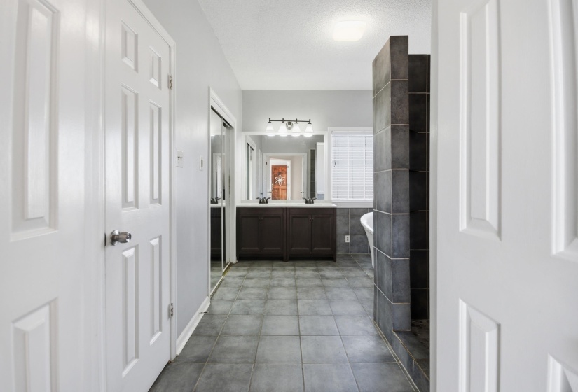 Bathroom featuring double vanity, a freestanding bath, light tile patterned flooring, and a textured ceiling