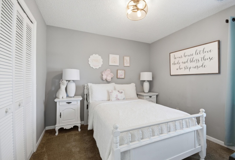 Bedroom with a closet, dark colored carpet, and a textured ceiling