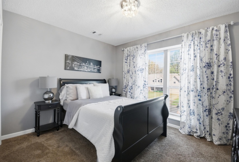 Bedroom with dark carpet, a textured ceiling, and hanging lights