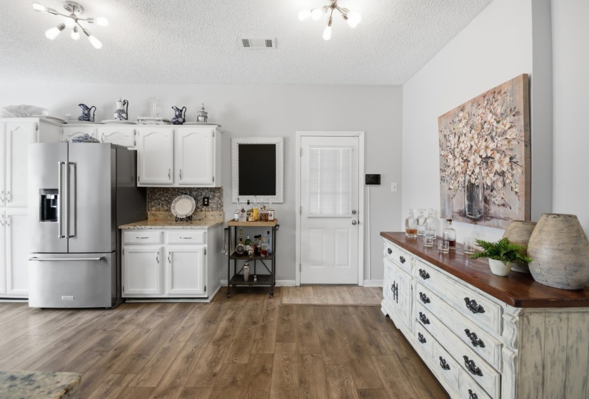 Kitchen with high quality fridge, white cabinetry, dark wood-style floors, tasteful backsplash, and a textured ceiling
