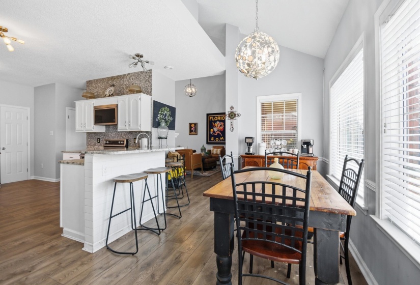 Dining space with dark wood-style flooring, a chandelier, and vaulted ceiling