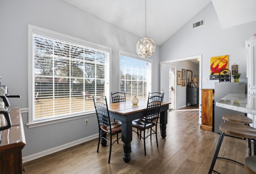 Dining area with vaulted ceiling, light wood finished floors, and hanging lights
