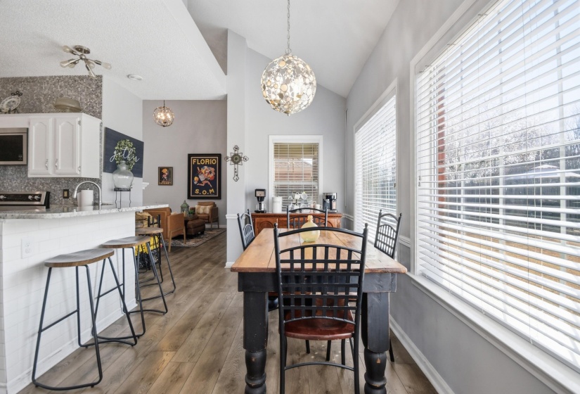 Dining space with dark wood-type flooring, hanging lights, and lofted ceiling