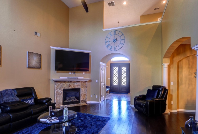 Living area featuring arched walkways, dark wood finished floors, a high ceiling, and a fireplace with flush hearth