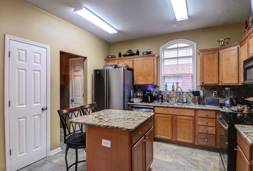 Kitchen featuring wood finish cabinets, a kitchen bar, black appliances, a kitchen island, and a textured ceiling
