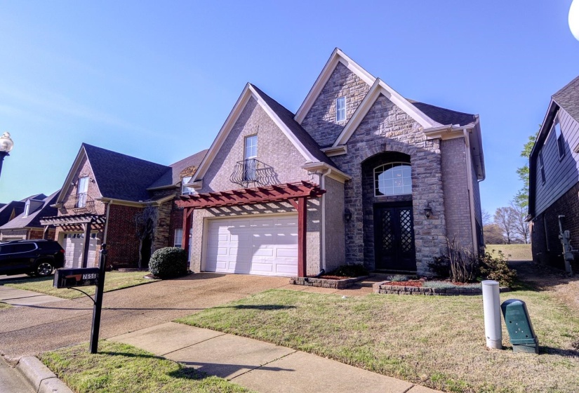 View of front of property featuring stone siding, concrete driveway, a front yard, a garage, and brick siding