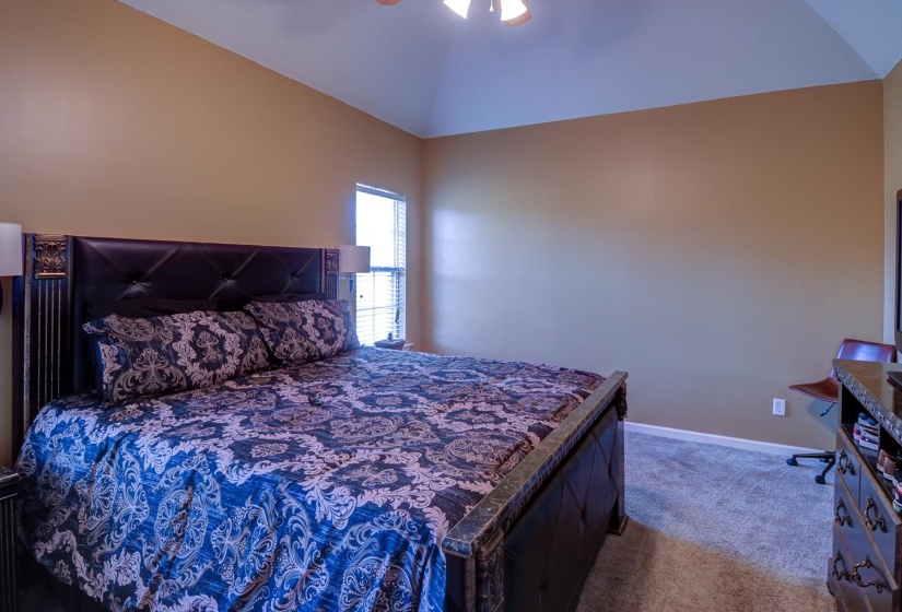 Bedroom with vaulted ceiling, carpet flooring, and ceiling fan