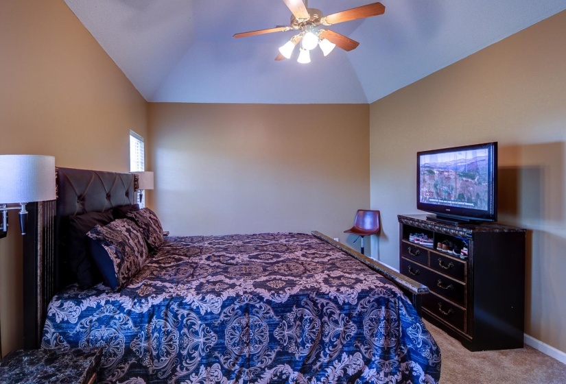 Carpeted bedroom with vaulted ceiling and ceiling fan