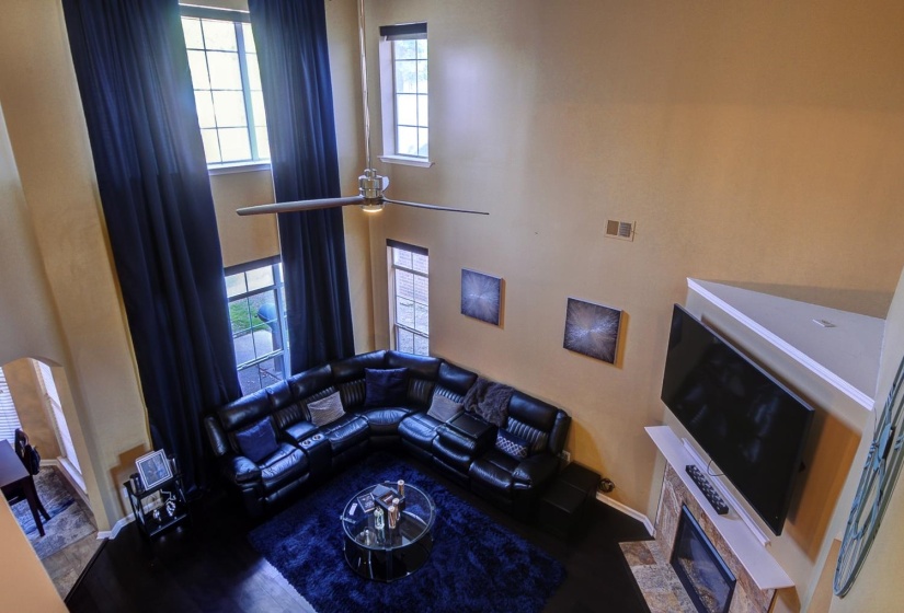 Living area featuring a high ceiling, a fireplace with flush hearth, a ceiling fan, wood finished floors, and arched walkways