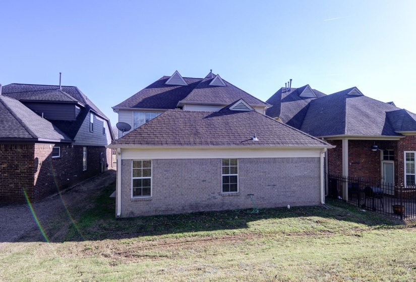 Rear view of property featuring roof with shingles and brick siding