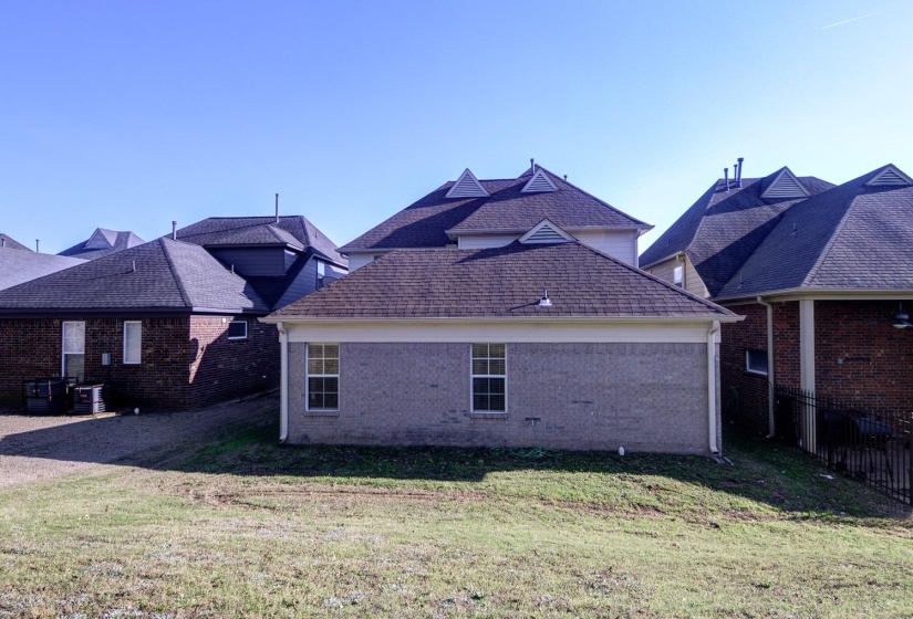 View of home's exterior with a yard, roof with shingles, and brick siding
