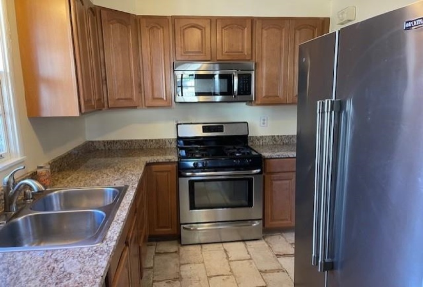 Kitchen featuring dark stone countertops, sink, and appliances with stainless steel finishes