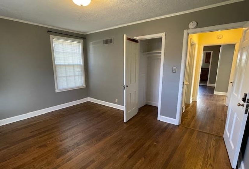 Unfurnished bedroom featuring a closet, dark wood-type flooring, a textured ceiling, and ornamental molding