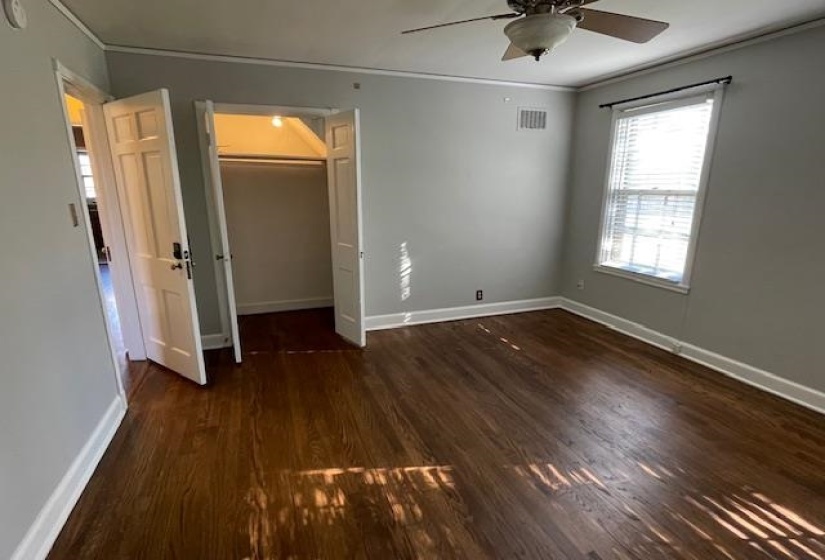 Unfurnished bedroom featuring dark wood-type flooring, ceiling fan, a spacious closet, ornamental molding, and a closet