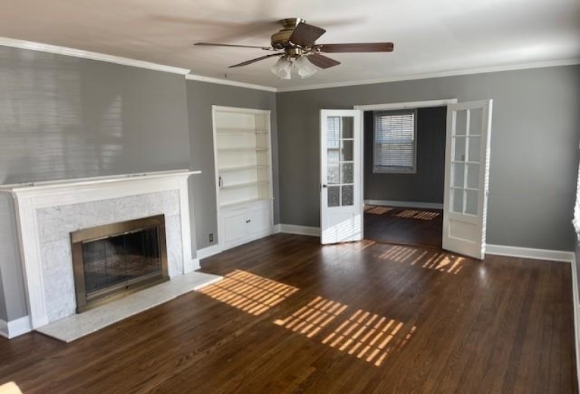Unfurnished living room with french doors, ornamental molding, ceiling fan, built in features, and dark hardwood / wood-style floors