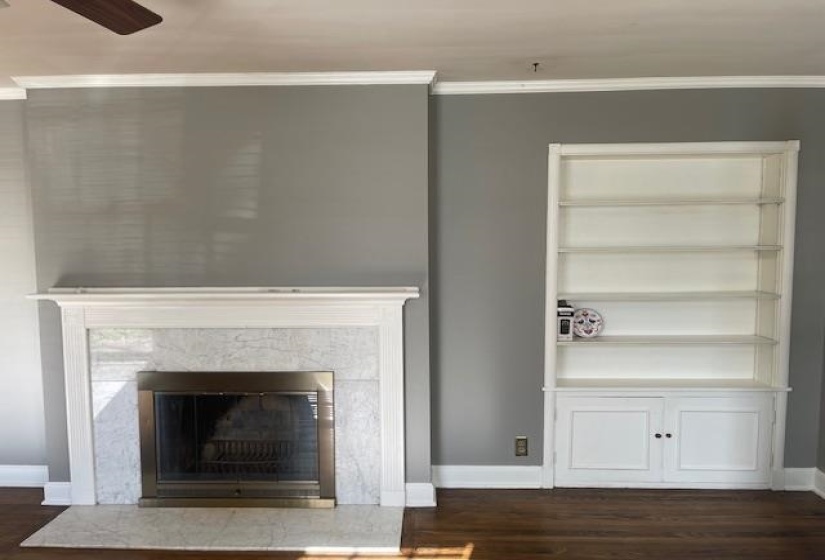 Interior details with hardwood / wood-style floors, crown molding, ceiling fan, built in features, and a fireplace
