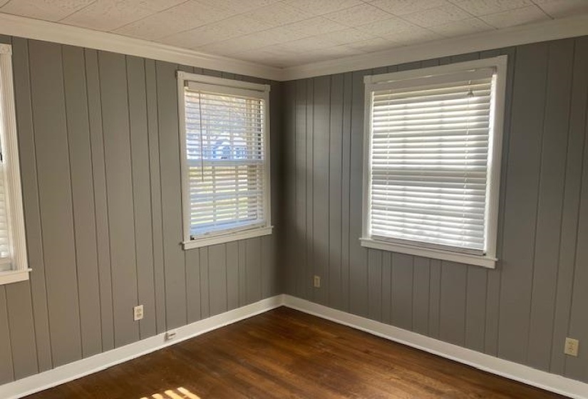 Empty room featuring dark hardwood / wood-style flooring, a wealth of natural light, ornamental molding, and wood walls