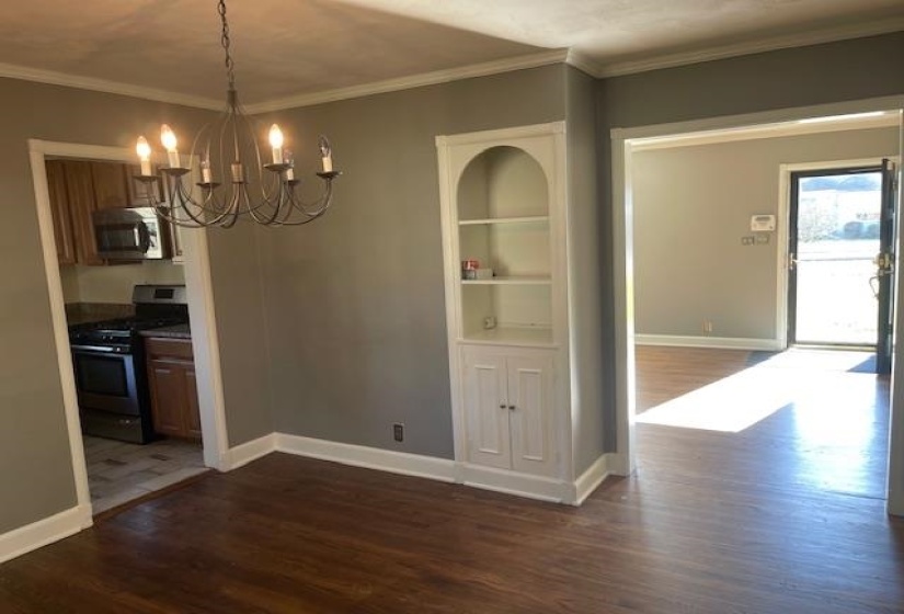 Unfurnished dining area featuring dark hardwood / wood-style flooring, crown molding, and a notable chandelier