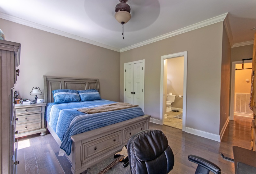 Bedroom featuring crown molding, ceiling fan, dark hardwood / wood-style floors, ensuite bathroom, and a closet