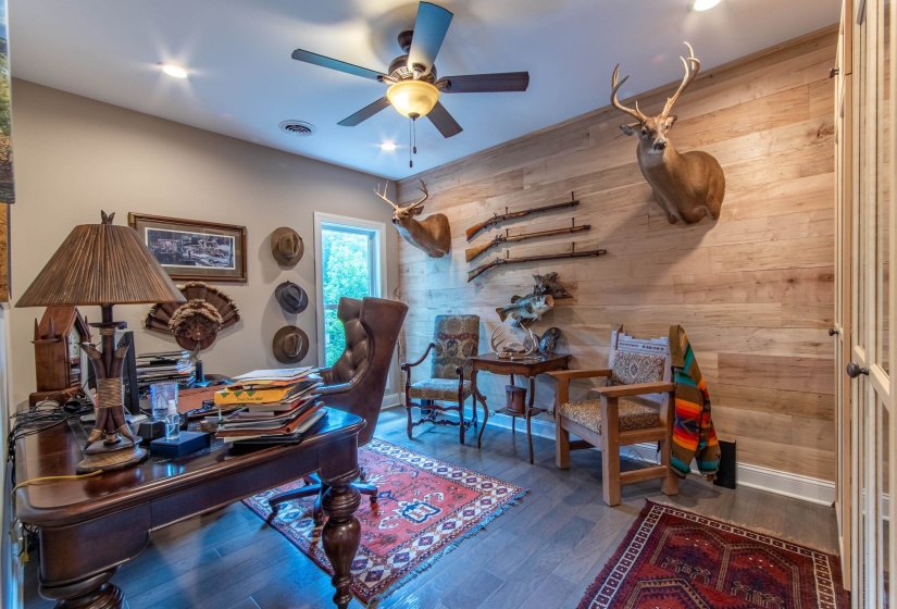 Office space featuring wood-type flooring, wooden walls, and ceiling fan