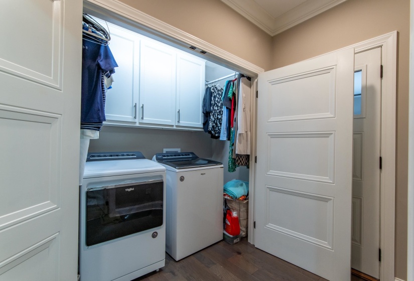 Clothes washing area featuring washer and clothes dryer, dark hardwood / wood-style floors, cabinets, and ornamental molding