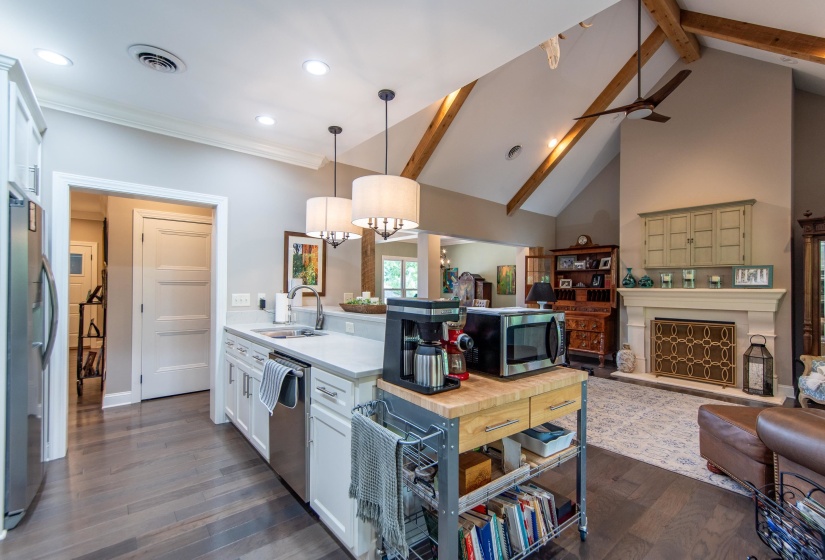 Kitchen with dark hardwood / wood-style flooring, beamed ceiling, appliances with stainless steel finishes, decorative light fixtures, and sink