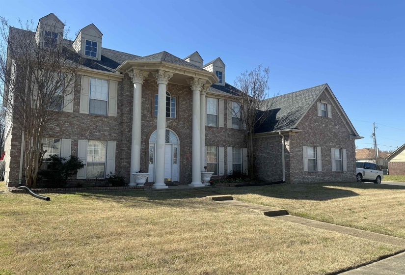 Greek revival house featuring brick siding, a front lawn, and a shingled roof