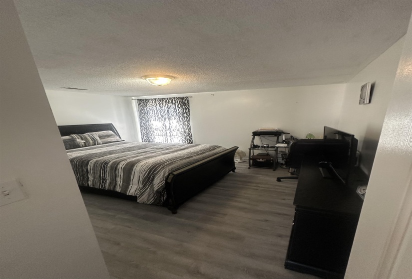 Bedroom with a textured ceiling and dark wood-style flooring
