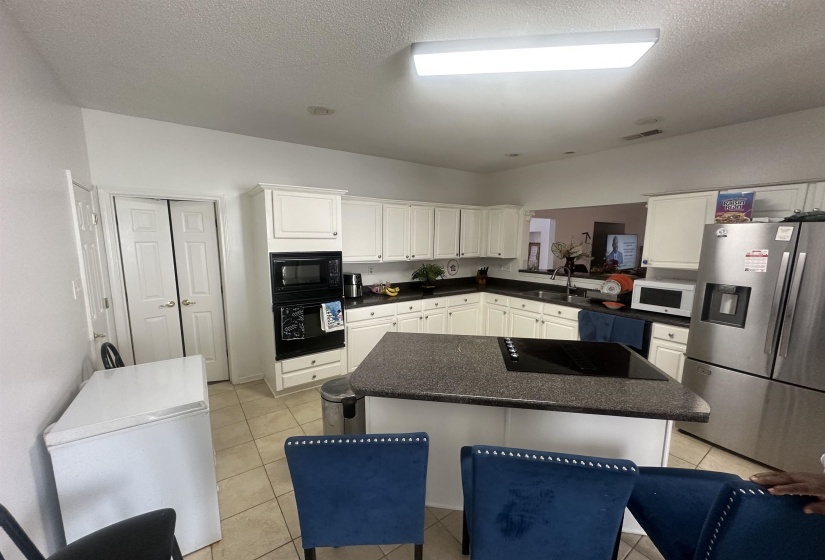 Kitchen featuring a center island, black appliances, dark countertops, white cabinets, and a textured ceiling