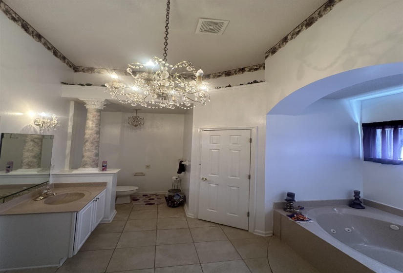Bathroom with vanity, a tub with jets, hanging lights, and light tile patterned floors