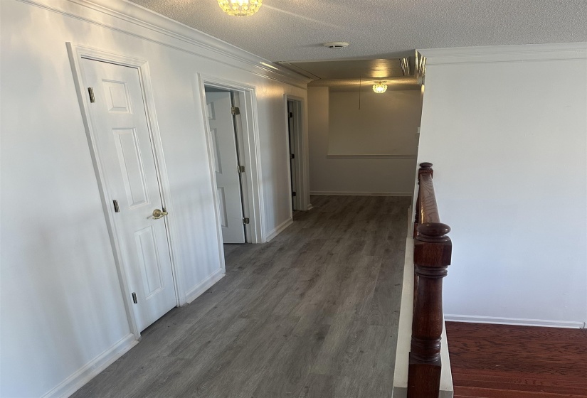Corridor featuring a textured ceiling, crown molding, and dark wood-style floors