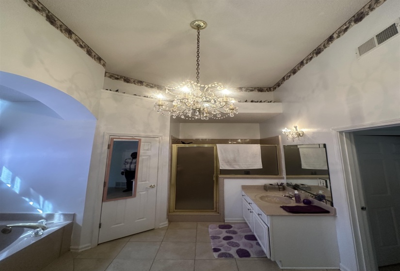 Full bathroom with vanity, a garden tub, a chandelier, a stall shower, and light tile patterned floors