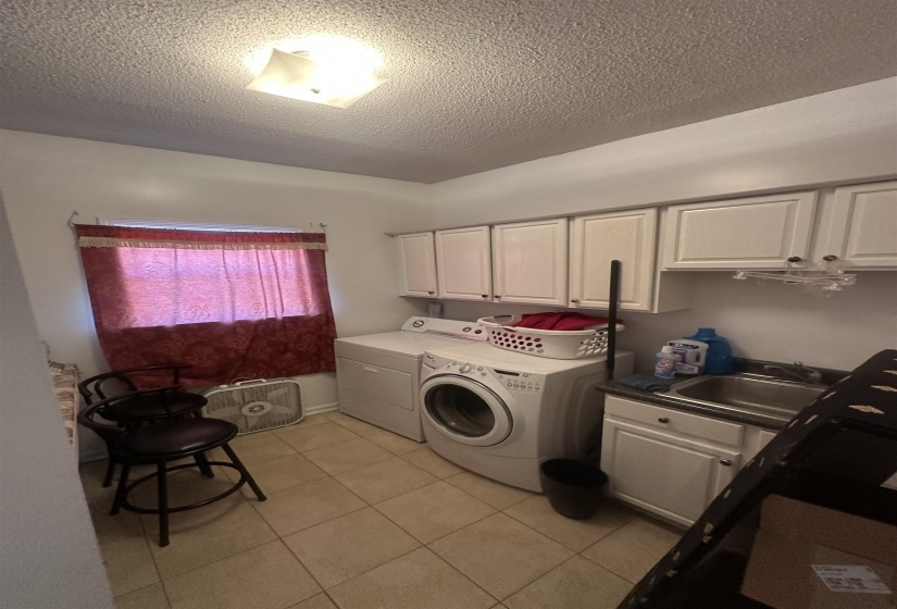 Laundry area featuring cabinet space, a textured ceiling, washer and clothes dryer, and light tile patterned floors
