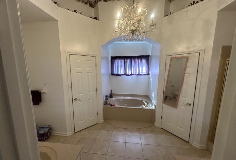 Full bath featuring suspended lighting, a bath, light tile patterned floors, a high ceiling, and vanity