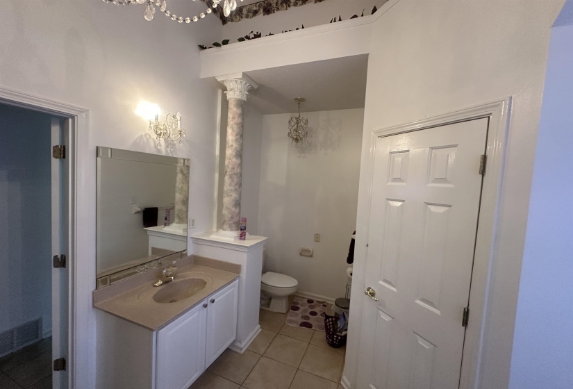 Half bathroom featuring suspended lighting, vanity, and light tile patterned floors