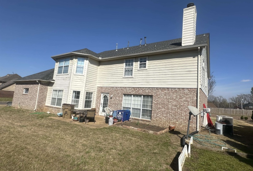 Back of property featuring a patio area, brick siding, a chimney, and a yard