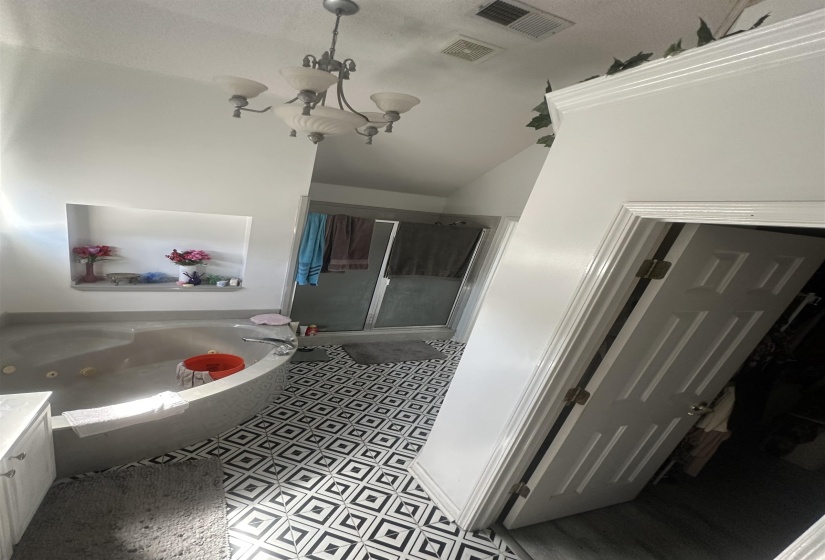 Bathroom featuring a shower stall, a tub with jets, and hanging lights