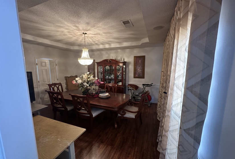 Dining room featuring a textured ceiling, dark wood-style floors, and a tray ceiling