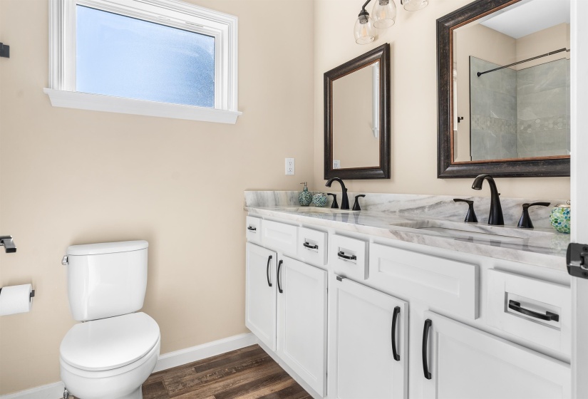 Full bath featuring double vanity, dark wood finished floors, and a shower