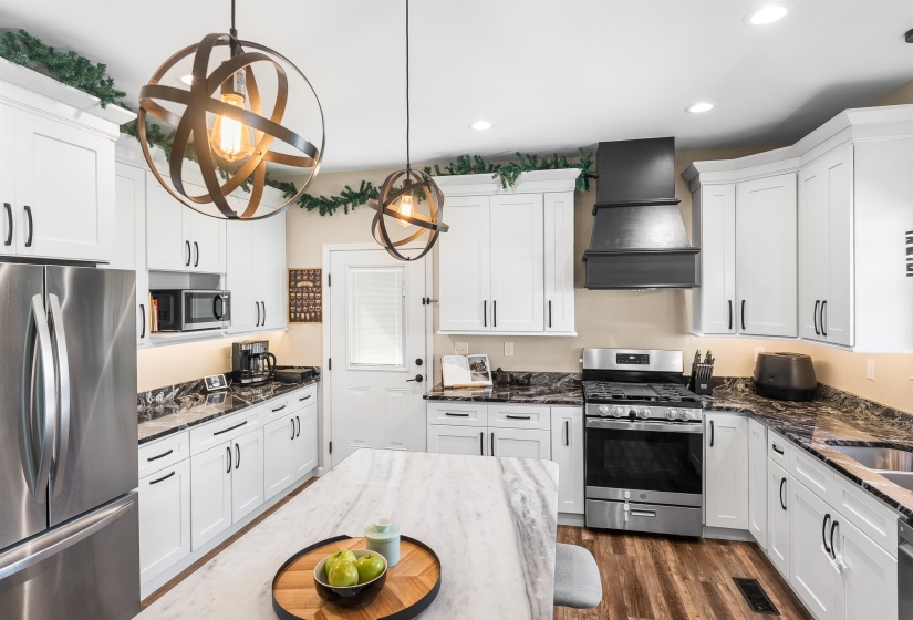 Kitchen featuring appliances with stainless steel finishes, dark stone counters, white cabinets, and recessed lighting