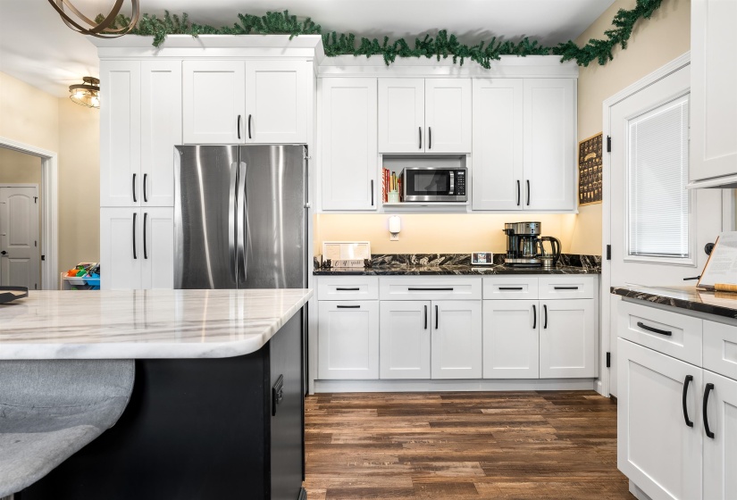 Kitchen with dark stone counters, stainless steel appliances, white cabinets, dark wood-style floors, and dark cabinets