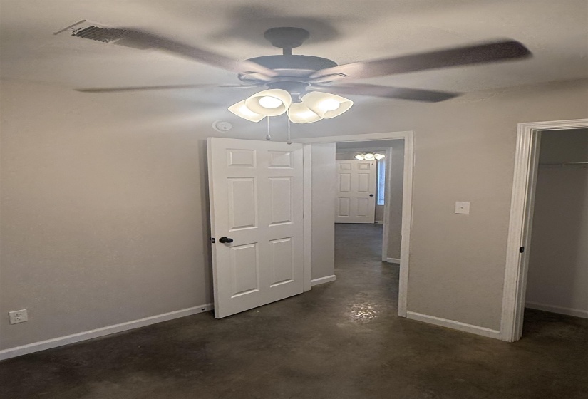 Unfurnished bedroom featuring finished concrete floors and a ceiling fan