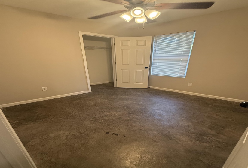 Unfurnished bedroom featuring ceiling fan, a closet, and concrete flooring