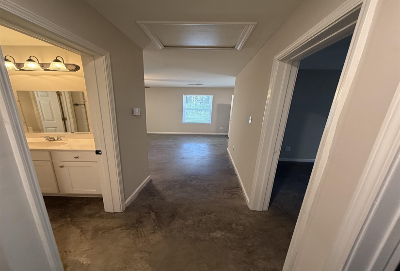 Hallway with unfinished concrete flooring and attic access